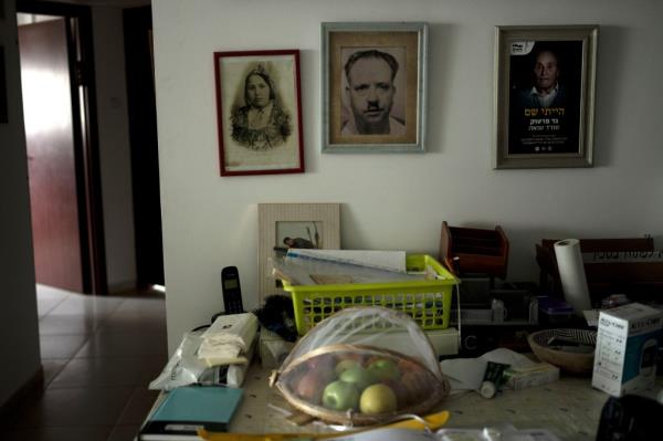 Pictures of the parents of Gad Partok, 93, a Tunisian-born Holocaust survivor, hang on the wall behind a table with a basket of fruit, in his home in southern Israel.