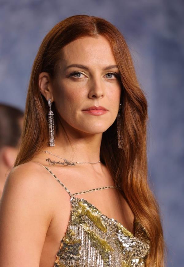 Riley Keough with long red hair in a gold dress at the 2023 Vanity Fair Oscar Party in Beverly Hills, California.